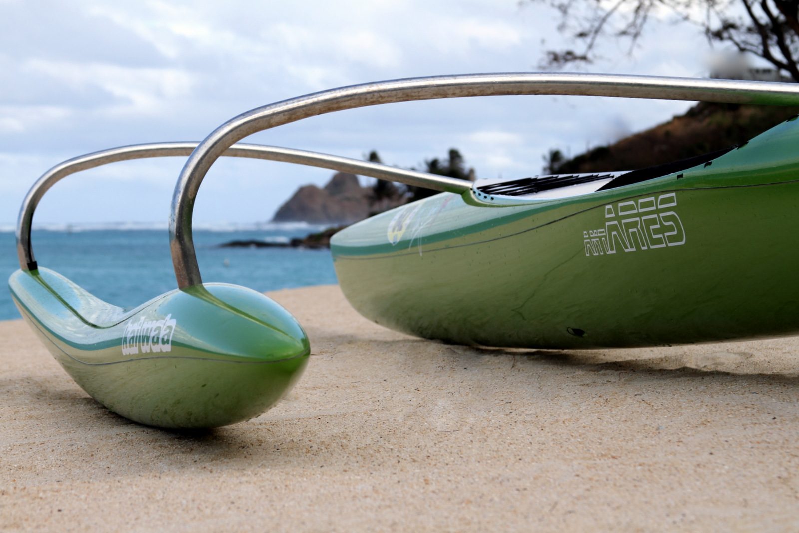 Close detail of a Kai Wa'a Ares outrigger canoe ama and iako on the beach