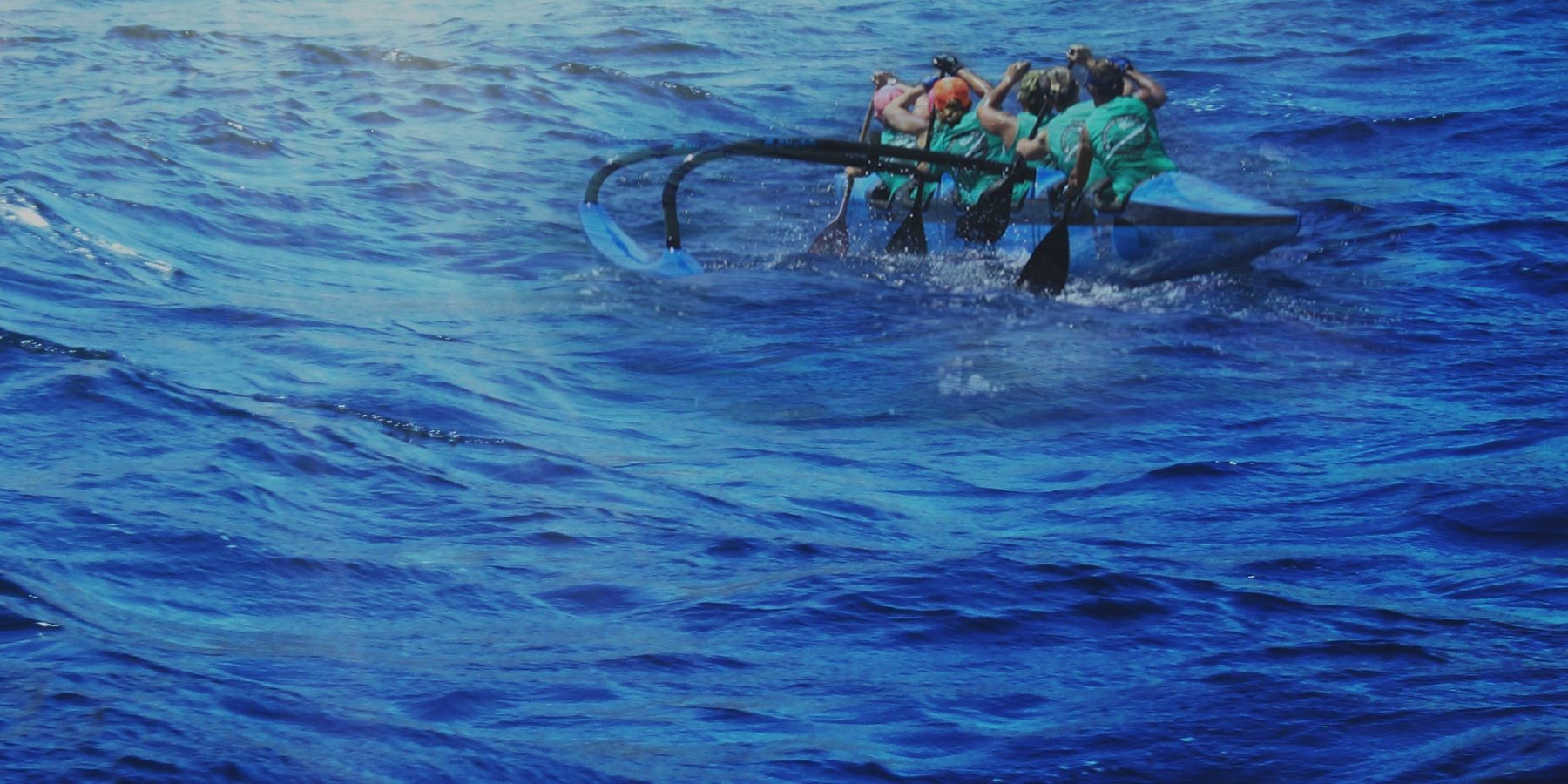 An OC6 crew paddling together on open water